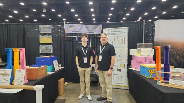 QuickFrame team at their NAHBE 2026 booth with colorful frames, sidebar displays, and hive equipment